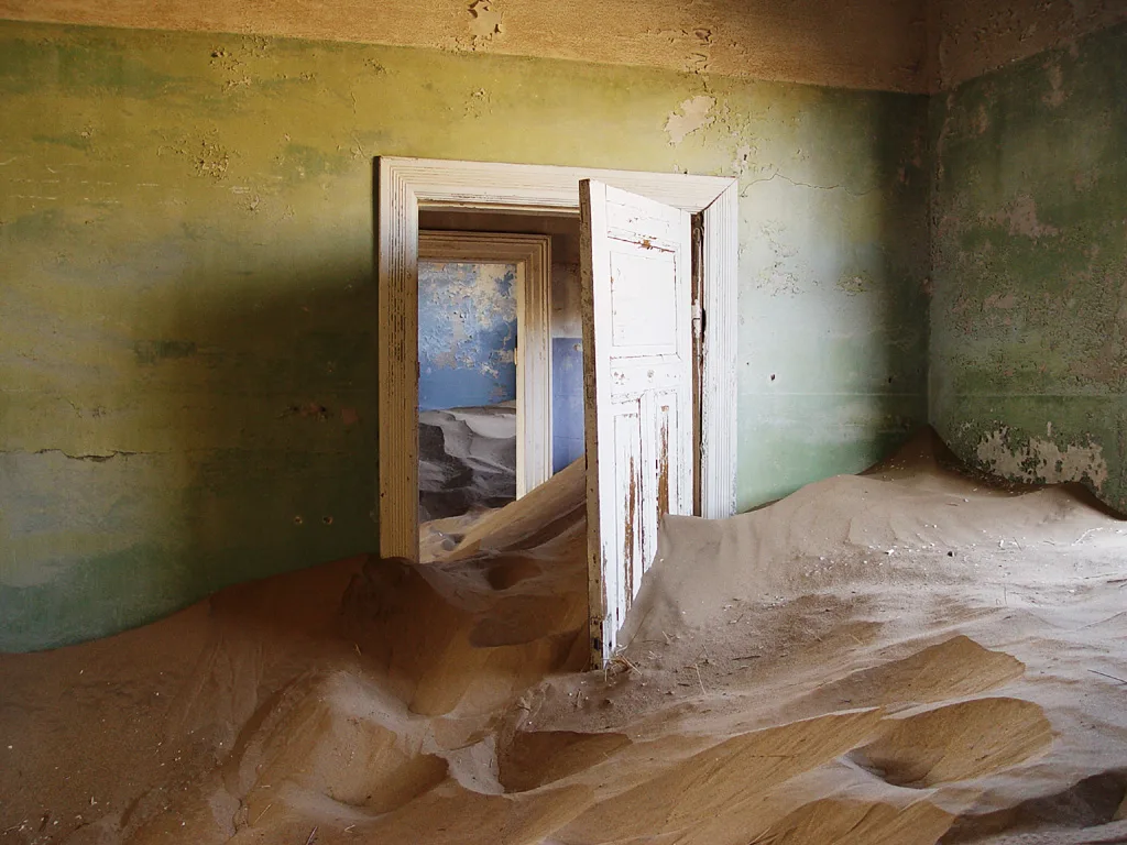 Sand drifting through the doorways of a deserted house in Kolmanskop